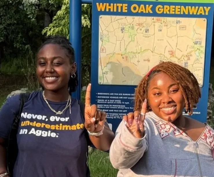 2026 summer fellows Genesis and Kierra pose by a greenway sign after an outing