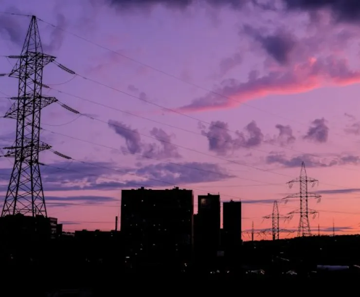A building silhouette in shadow against a colorful sunset next to power lines.