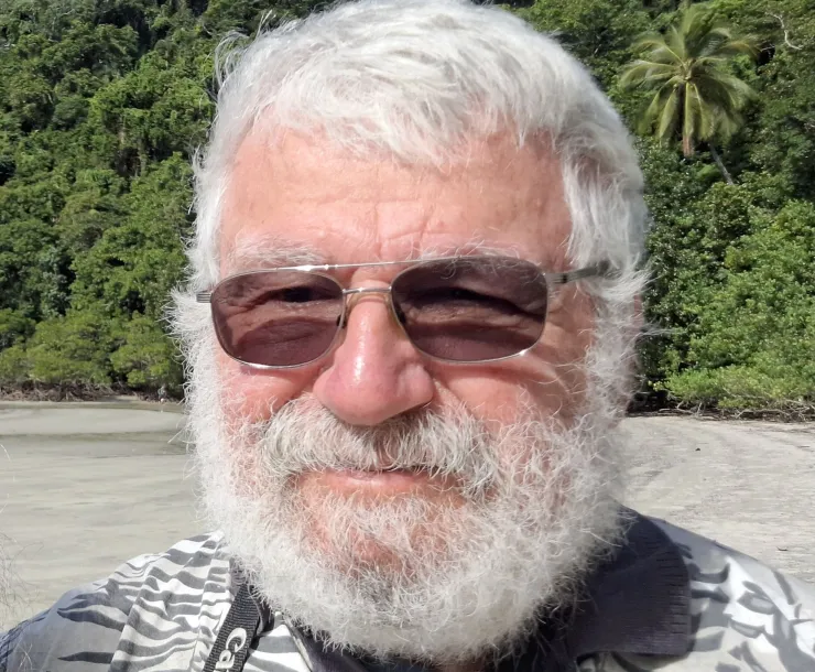 Alex Mintzer at a beach with green trees along the edge