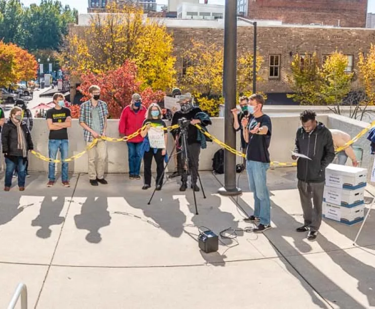 Co-author Brady Watson of Sunrise addresses rallygoers in front of 4000 comments in stacked boxes about to be delivered to the TVA Board meeting. Co-author Isabella Killius stands third from right.jpg