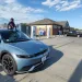 A child sits on top of a Hyundai Ioniq 5 electric vehicle as it charges at an Electrify America station.