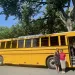 Yellow electric school bus with two advocates in front of it 