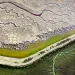 A levee divides a parched salt pond from a burgeoning wetland.