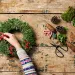 Overhead view of an arrangement of a Christmas wreath or garland being made by a teenage girl. Various tools and decorative pieces are laid out waiting to be used. 
