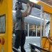 Two men retrofit a yellow school bus