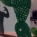 Illustration shows a large saguaro cactus with the shadow of a devil figure behind it plus a refinery and people standing nearby.