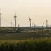 Wind turbines and power lines stretch across field