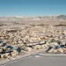 Aerial photo shows a flat housing subdivision covered in snow with mountains in the background.