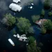 Overhead photo shows houses almost completely submerged in water, treetops, and floating items.