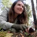 Thea Chesney smiles and reaches for a morel on the forest floor.