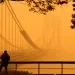 A man talks on his phone as he looks through the haze at the George Washington Bridge from Fort Lee, N.J., Wednesday, June 7, 2023.
