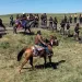 A row of Native Americans on horseback face off against a line of North Dakota police officers near the Dakota Access Pipeline