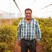 Farmer in the middle of his crops smiling 
