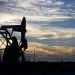 Silhouette of an oil well against a sky at sunset