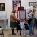 Lauren Miracle, right, holds her son Dawson, 1, as she helps her daughter Oaklynn, 3, fill out a child's practice ballot before voting herself at a polling location in the Washington Township House in Oregonia, Ohio, Tuesday, Nov. 7.
