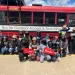 A group of students from Detroit pose in front of a red school bus.