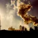 Smoking chimney at sunset on industrial buildings complex