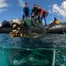 Kevin O'Brien and two others pull a huge tangled net out of the ocean into a dinghy.