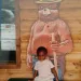 Young Deidra Goodwin sits on a bench by a Smokey the Bear mural
