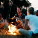 People sitting in a meadow around a campfire at dusk