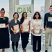 5 people stand in a row holding awards