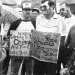 Two men hold protest signs