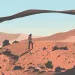  A hiker walks up a redrock hill toward a sandstone arch in the desert