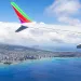 A plane flying over blue waters off the coast of Hawaii
