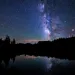 A purple nighttime sky full of stars and its reflection in a lake