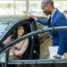 Car dealer explaining new car features to female customer at showroom.