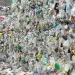 Man examines bales of plastic waste bottles