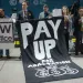 Protestors at COP29 hold a sign that says "Pay Up for Adaptation"