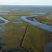 Aerial view of a sprawling muddy tundra and oil infrastructure in Alaska
