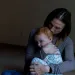 Amy Dishion hugs her toddler, who is looking over her shoulder at the camera
