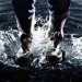 Close-up of someone's legs in rain boots as they splash in dark water