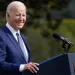 President Joe Biden smiles at a podium 