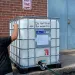 A large, plastic tank of water rests on a house's front porch