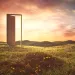  Photo illustration shows a door opened in a door frame in the middle of a field of grass and wildflowers, with an orange cloudy sky above.