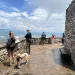 back view of a group of people looking out at the horizon from a brick structure