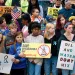 Students and adults of different races stand in front of Florida’s Department of Environmental Protection holding signs including "Oil and Water Don't Mix," "Kill the Drill," and "Save Apalachicola Bay."