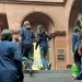 Students and adults from CRETF wearing black pants and dark-blue tops walk up the steps of the New York State Capitol.