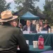 People sit at a table and speak to a crowd outdoors