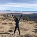 A person stands with their arms outstretched on public lands