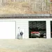 A man stands before a fire department building with solar panels affixed to the roof. 