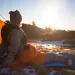A girl looking toward the sun from her tent while snuggled in her sleeping bag