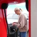 A driver, seen through an EV charging station, powering her EV SUV.