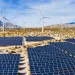 A field of solar panels and windmills in the desert.