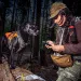 Winnie, one of CK9's sniffer dogs, looks on as handler Jennifer Hartman logs data for fisher scat.