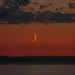 A crescent moon in the warm sunset glow.