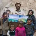 Outside a house he's building for his family and surrounded by his children, Muhammad Jan, a 46-year-old builder and plasterer, displays photos of Biscayne National Park in Florida and Glacier National Park.